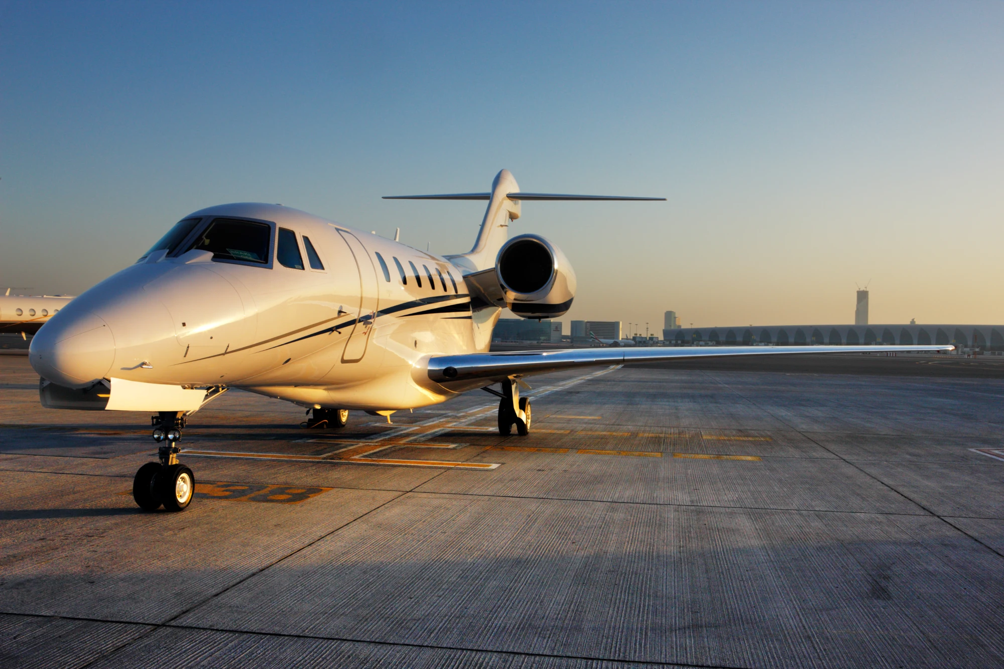 Private jet on airport runway at sunrise.