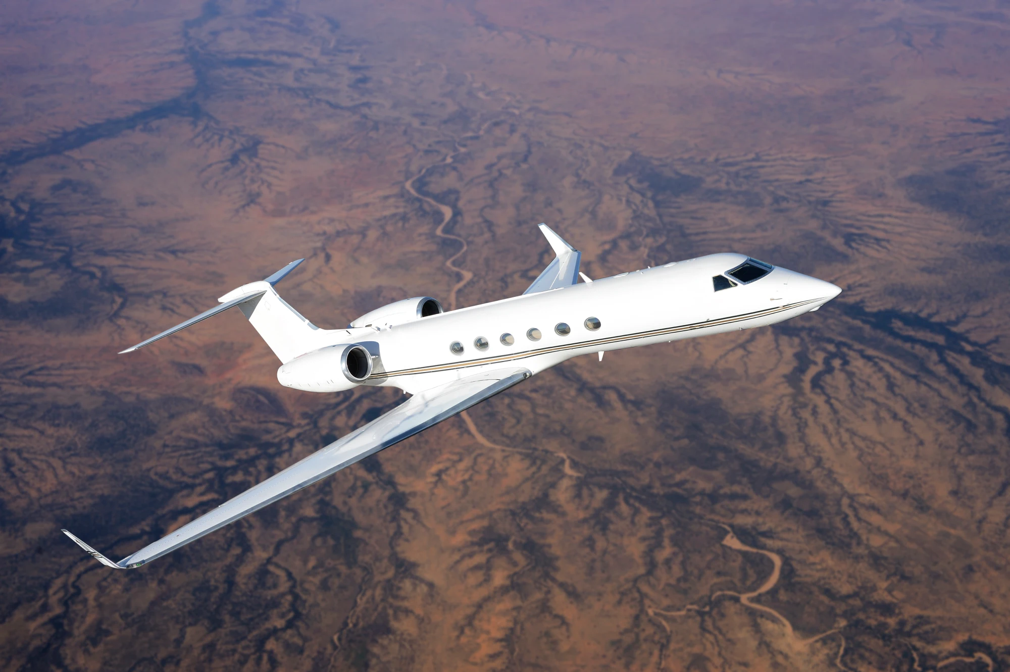 Private jet flying over desert landscape.