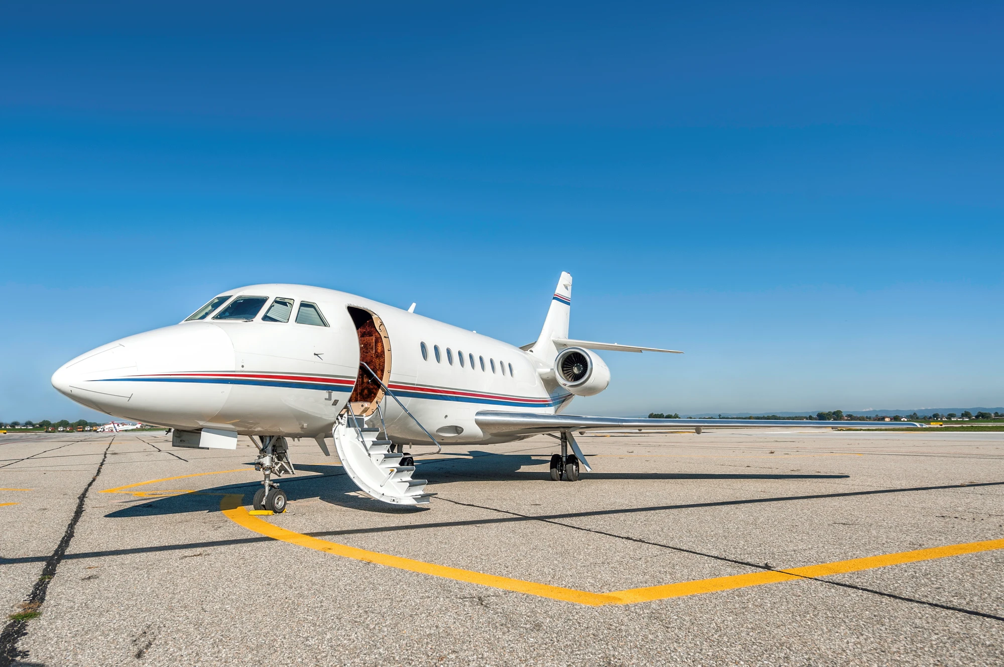 Private jet on airport runway under sky.