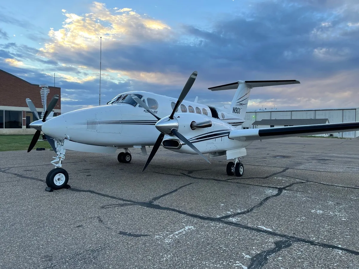 White airplane parked on tarmac at sunset.